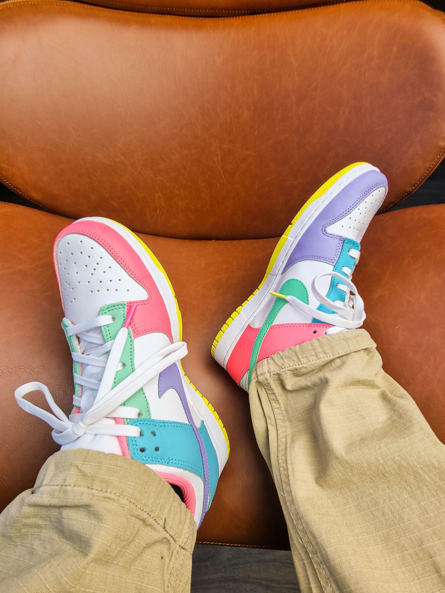 Pastel Nike Dunks worn on a leather chair